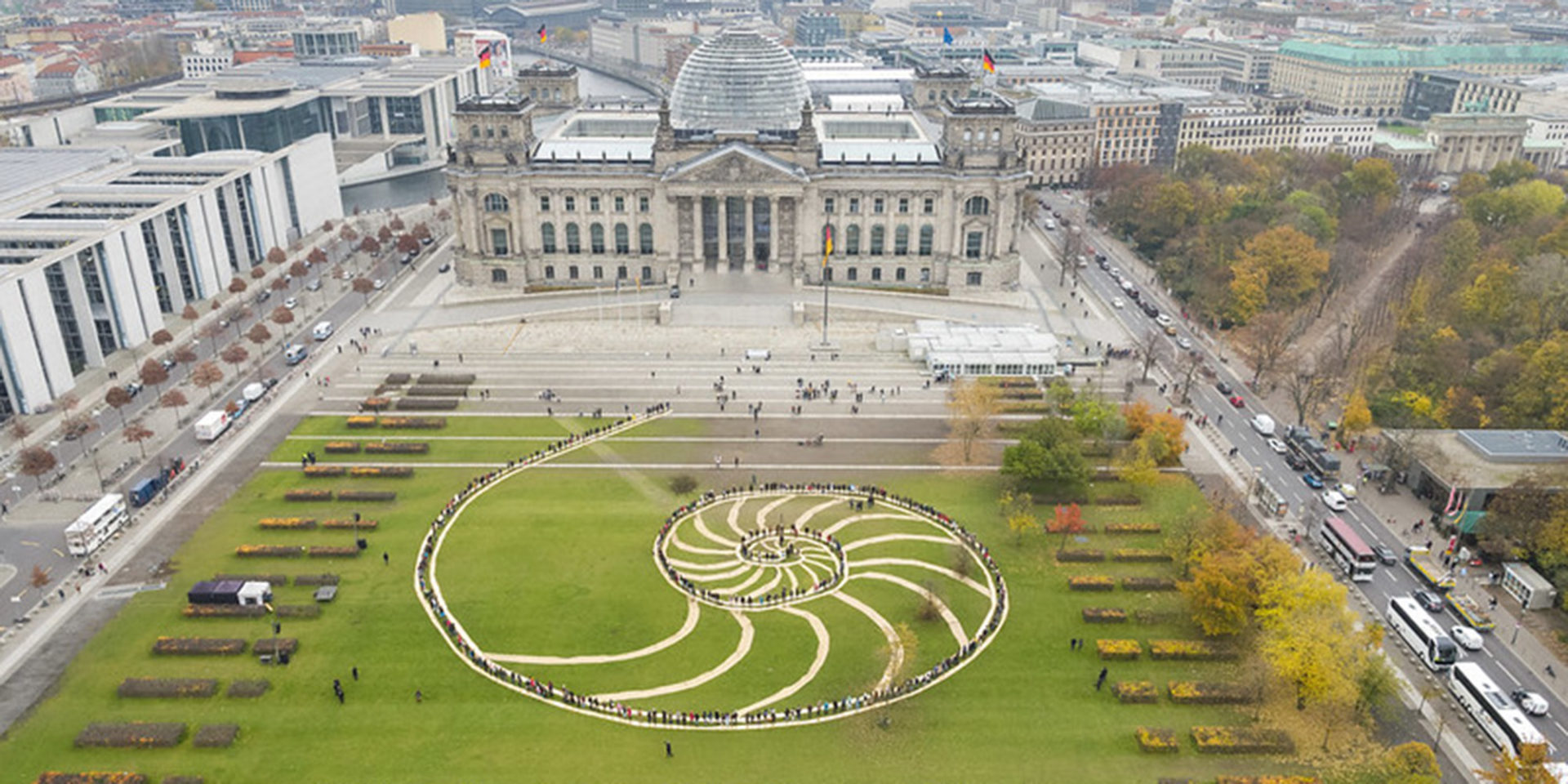 Die Luftaufnahme zeigt den Reichstag in Berlin mit der davor liegenden Wiese, auf dieser ist der Schriftzug "Democracy for Future" zu lesen.