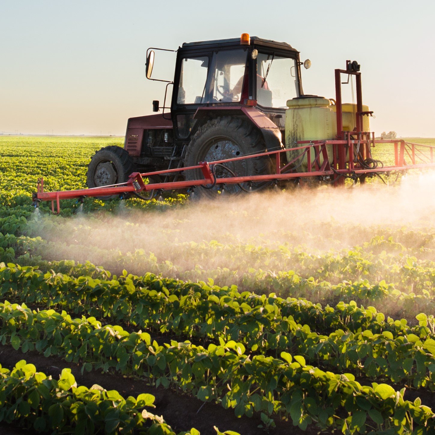 Ein Landwirt fährt mit seinem Traktor über ein Feld und wässert.