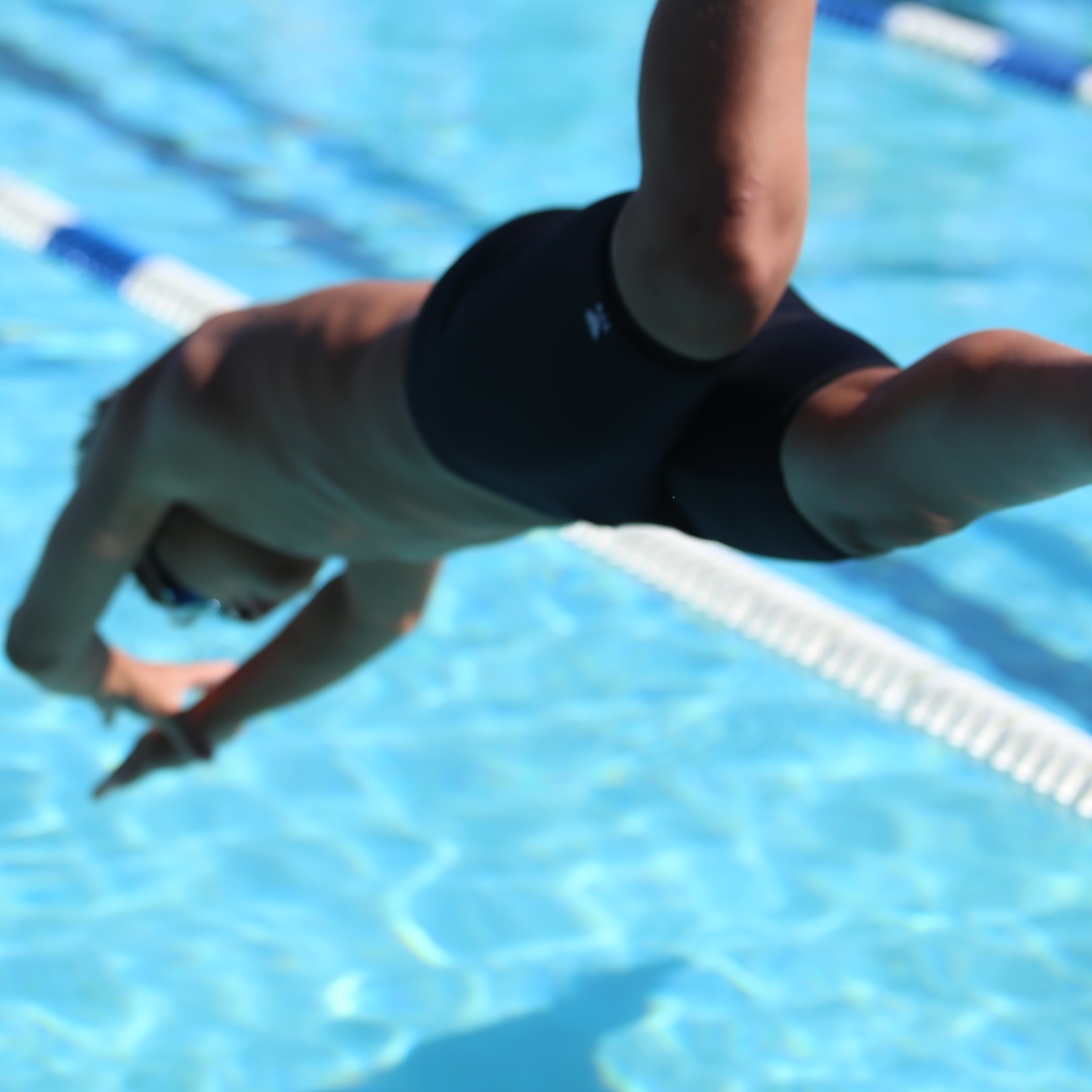 Ein Junge springt kopfüber in das Schwimmerbecken eines Freibads.